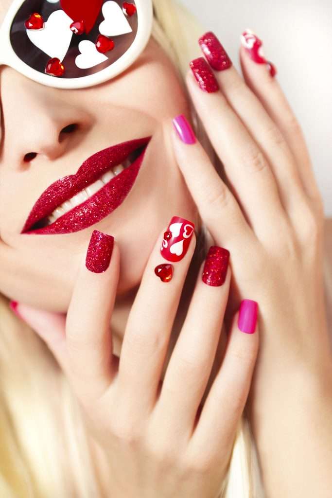 50906063 - manicure and makeup with red sequins and hearts of different shapes and colors on the girl with glasses with long white hair.